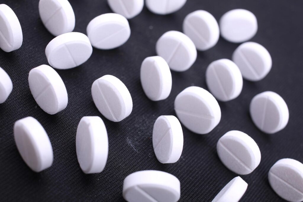 White pills scattered on a black surface.