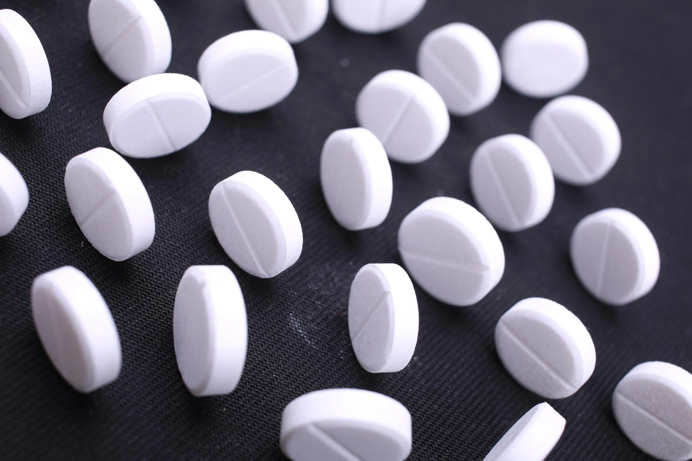 White pills scattered on a black surface.