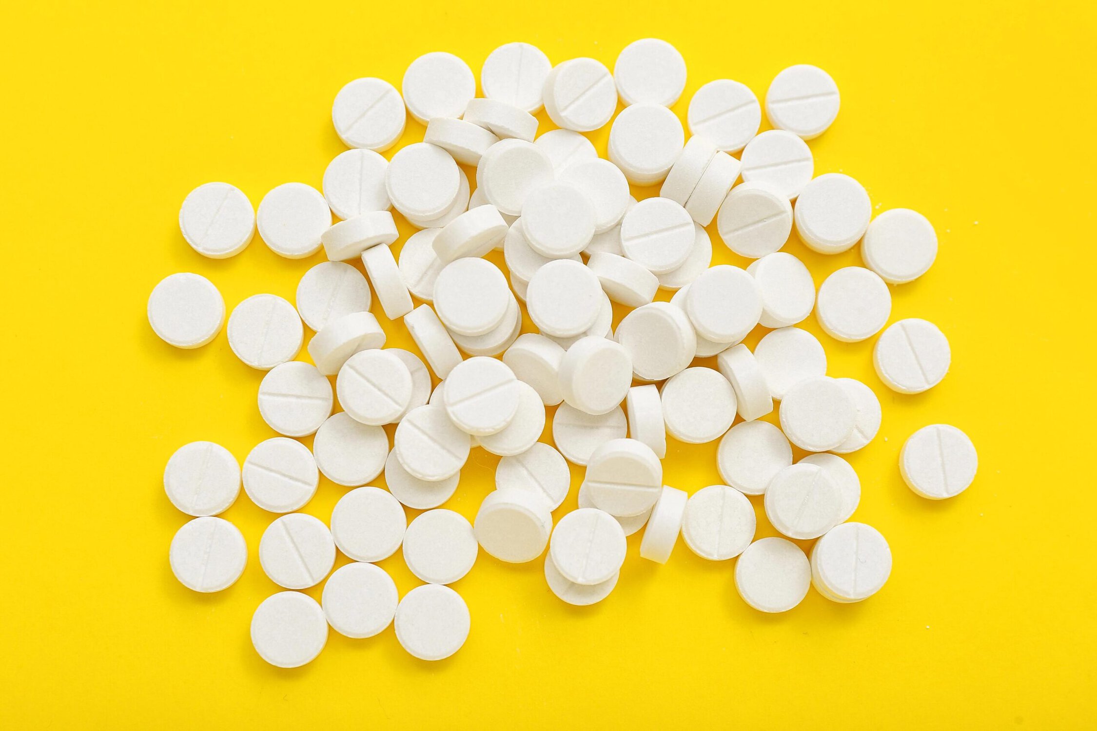 White pills scattered on a yellow background.