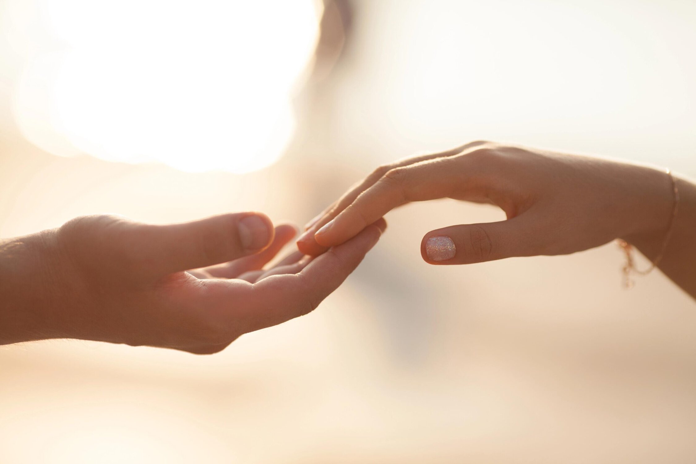 A woman gently holding a man's hand in a comforting gesture.