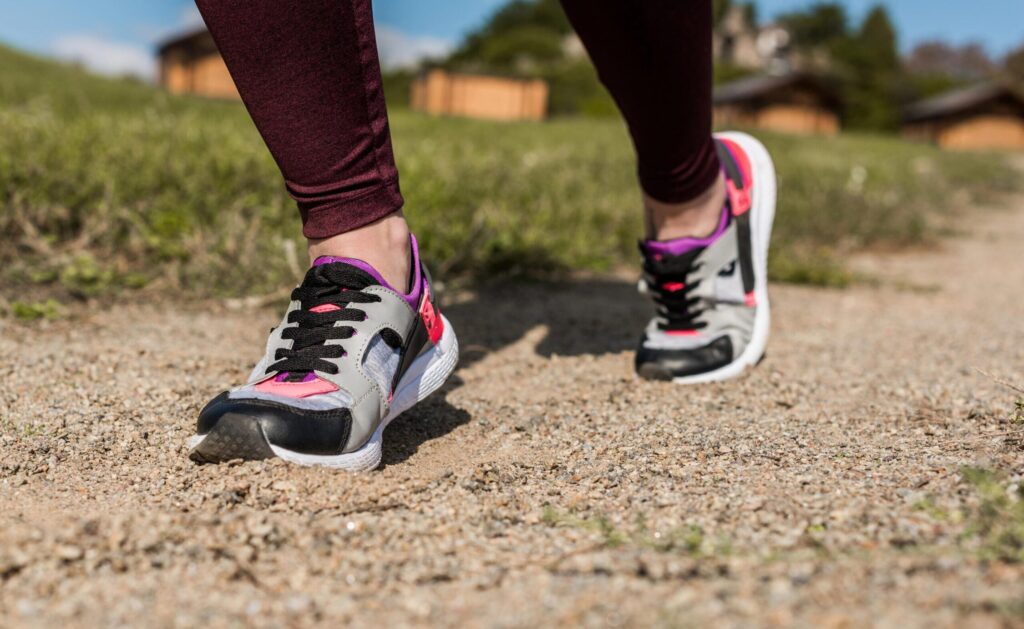 Running shoes on a gravel path outdoors in a park or natural setting.