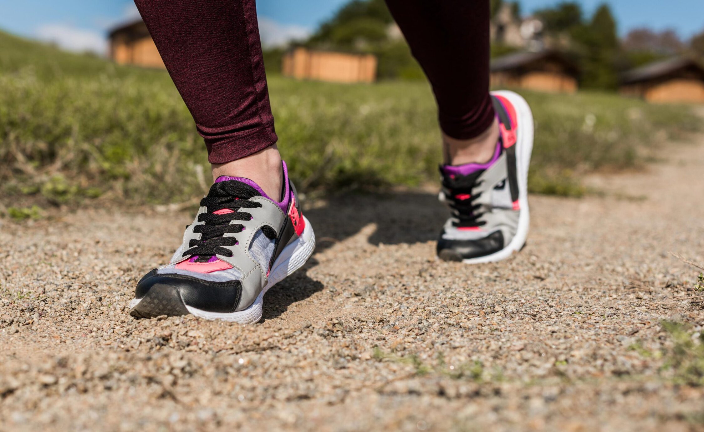 Running shoes on a gravel path outdoors in a park or natural setting.