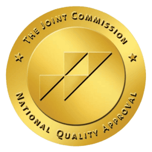A gold seal with "The Joint Commission" and "National Quality Approval" text surrounding a stylized.